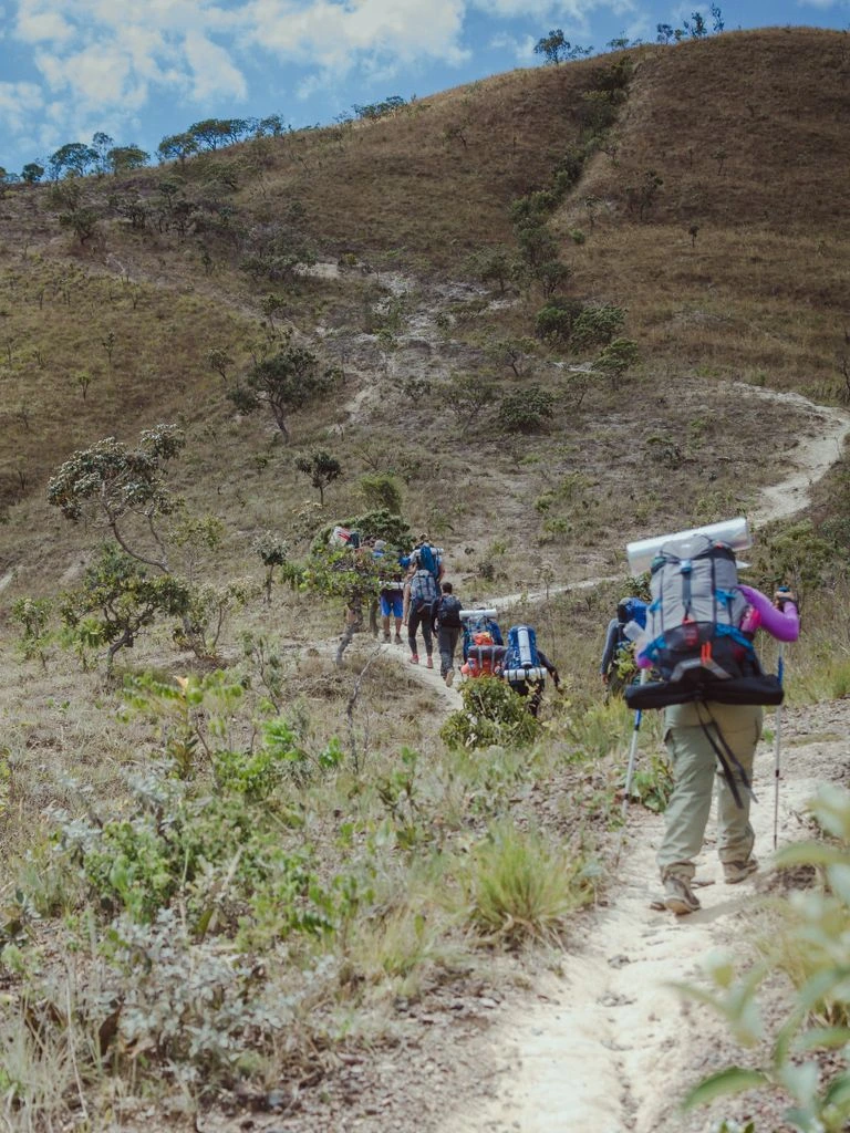 Trekker brasileiro consultando carta topográfica anotada sobre pedra granítica