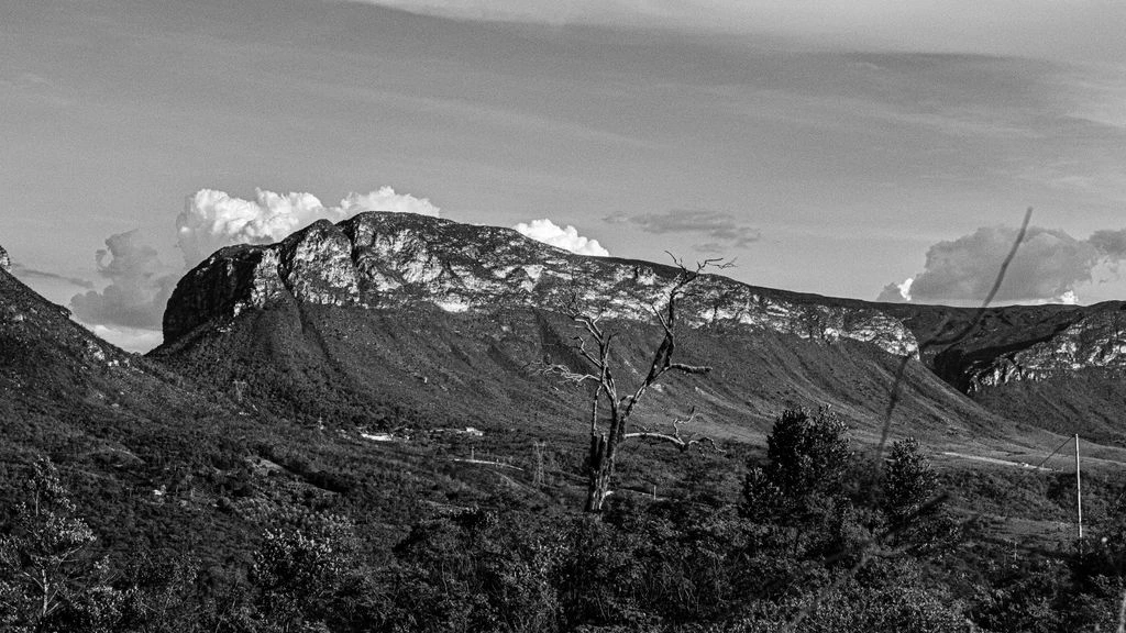 Chapada Diamantina com morros de arenito vermelho, vegetação de cerrado e piscina natural ao fim da trilha